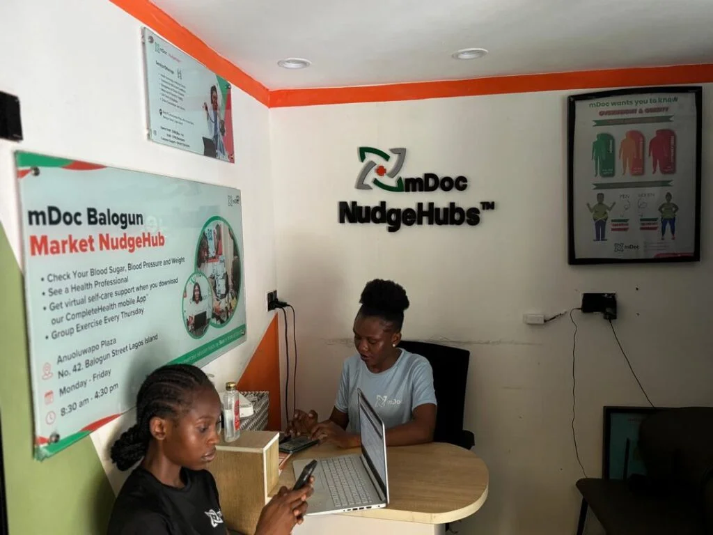 Health coach carrying out chronic disease screening on a woman at a market hub in Lagos.