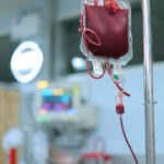 Labelled bags of donated blood stored on shelves inside a refrigerated hospital blood bank.