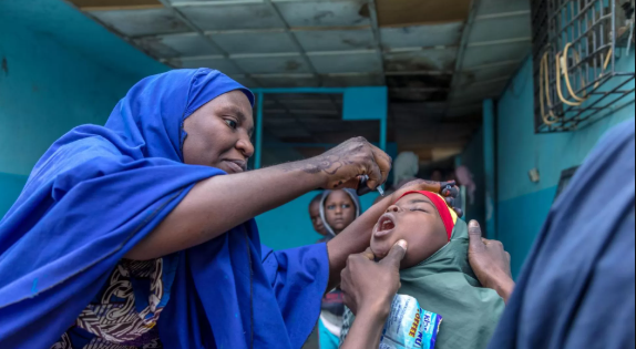 As Nigeria vaccination campaign targets 106 million, health worker administers oral vaccine to a child